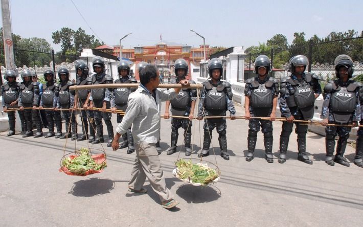 KATHMANDU – Een groenteverkoper passeert een kordon agenten in Kathmandu. Foto EPA