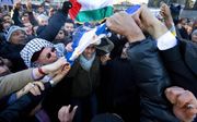 ROTTERDAM - Demonstranten verbranden een Israelische vlag en verscheuren hem met hun tanden. Demonstranten voeren vrijdag actie op de Coolsingel in Rotterdam tijdens een actie tegen de Israelische bombardementen op de Gazastrook. Foto ANP