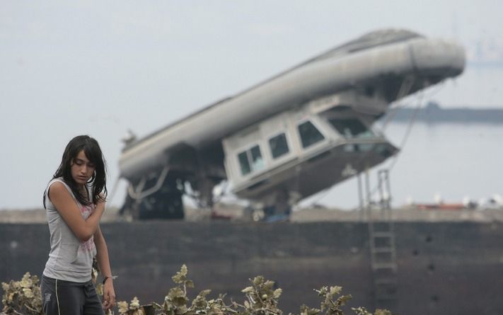 TALCAHUANO – Een jonge vrouw liep dinsdag langs de zwaar door de aardbeving en tsunami getroffen haven van Talcahuano, een stad aan de westkust van Chili. Het totale aantal doden door de natuurramp wordt momenteel geschat op 795, maar zal nog verder oplop