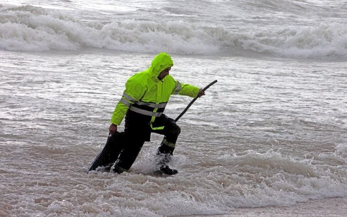 Een man haalt een brokstuk van het vliegtuig uit zee. Foto EPA