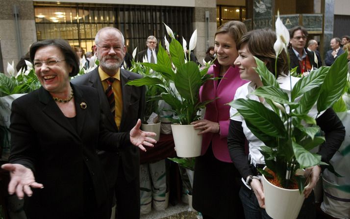 Verbeet (l), voorzitter van de Tweede Kamer, reikt een bureauplant uit aan politici en ambtenaren in de Statenpassage van de Tweede Kamer. Foto ANP