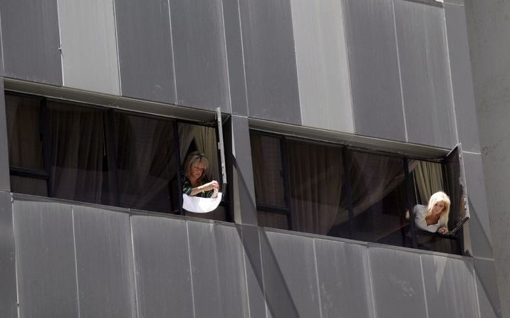 Mensen in quarantaine kijken uit het raam van het hotel in Hong Kong. Foto EPA