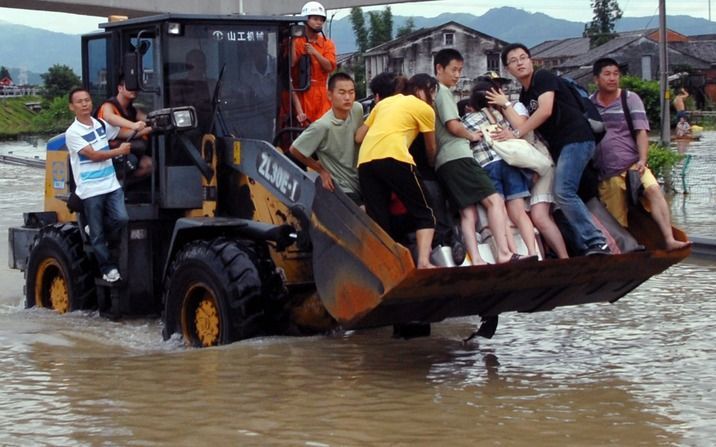 CANGNAN – Gedupeerde Chinezen in de Oost-Chinese provincie Zhejiang reden maandag mee op een bulldozer, om aan de vloedstroom, veroorzaakt door de tyfoon Morakot, te ontkomen. Foto EPA