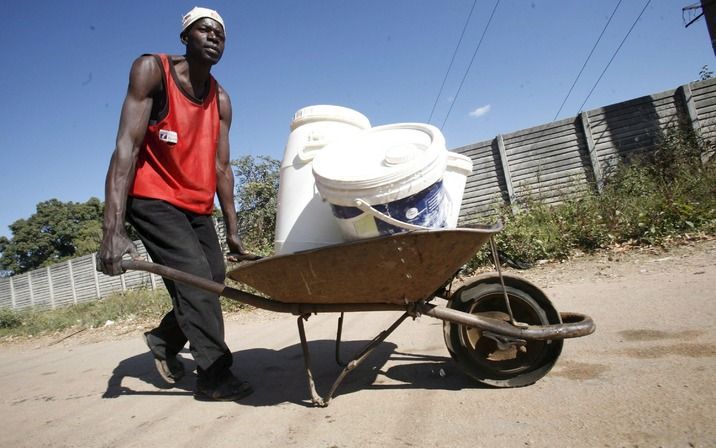 Een Zimbabwaan met een nieuwe voorraad drinkwater. Volgens hulporganisatie AzG is langs de grens met Zuid-Afrika sprake van een humanitaire crisis. Foto EPA