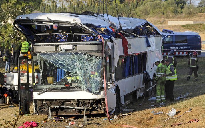 Brandweermannen maandagochtend bij de bus die op de A7 bij de Spaanse stad Gerona kantelde. Foto ANP