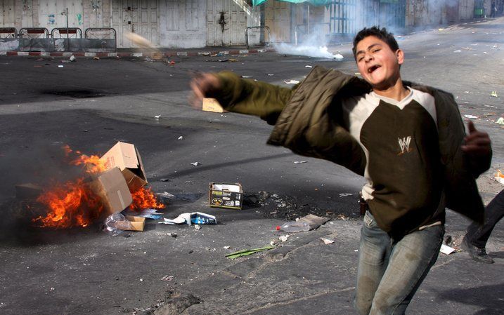 JERUZALEM - Een jongen gooit stenen tijdens onenigheid op de Westbank. Foto EPA