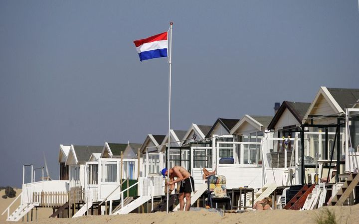 IJMUIDEN - De vlag wordt gehesen bij een strandhuisje op het strand in Ijmuiden. De meivakantie start zonnig met een temperatuur van 20 graden. Foto ANP