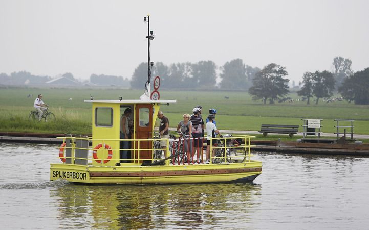 SPIJKERBOOR - Fietsers nemen zaterdag het pontje Jan Hop nabij Spijkerboor in Noord-Holland. Op deze nazomerse dag scheen de zon volop, maar waren later op de dag ook enkele wolkenvelden. Het was warm en er stond vrijwel geen wind. ANP