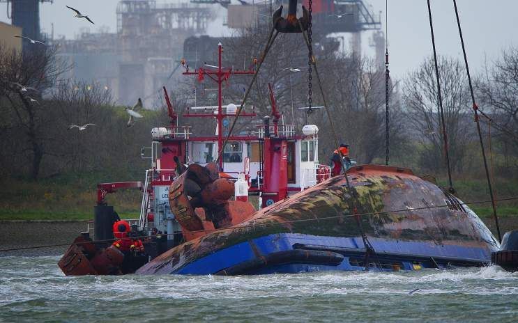 De sleepboot die donderdag op de Nieuwe Waterweg kapseisde wordt vrijdag in de haven van Hoek van Holland geborgen. Foto ANP