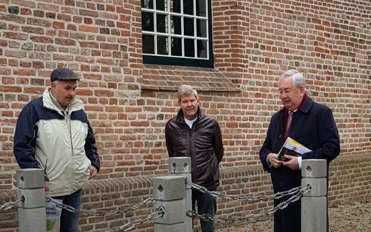 V.l.n.r.: Ars Kuijntjes, lid van de werkgroep De Vier Heerlijkheden; Gerrit Ermstrang, lid van de dorpsraad Brakel; en ds. Lodewijk van Wingerden, bij het graf van zijn grootvader Lodewijk Verheul naast de kerk in Brakel. beeld De Vier Heerlijkheden