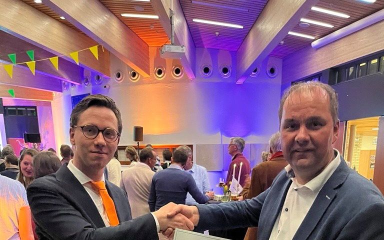 Mannen in een blauw pak drukken elkaar de hand.