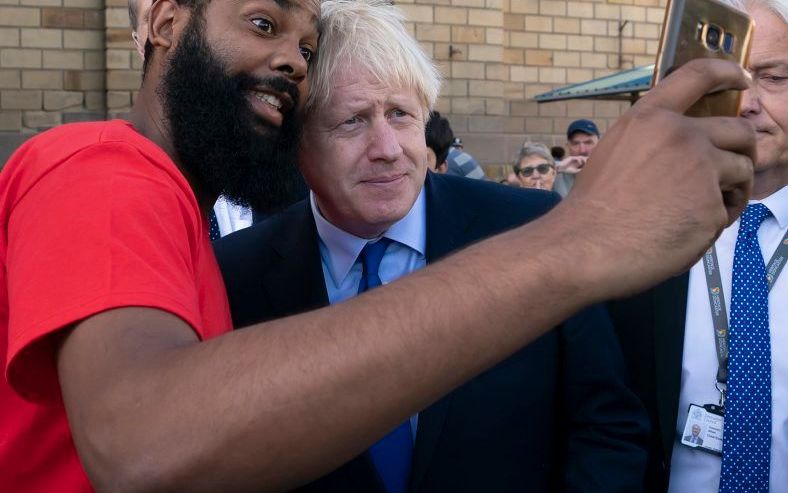 De Britse premier Johnson gaat in Doncaster op de foto met iemand uit het publiek. beeld AFP