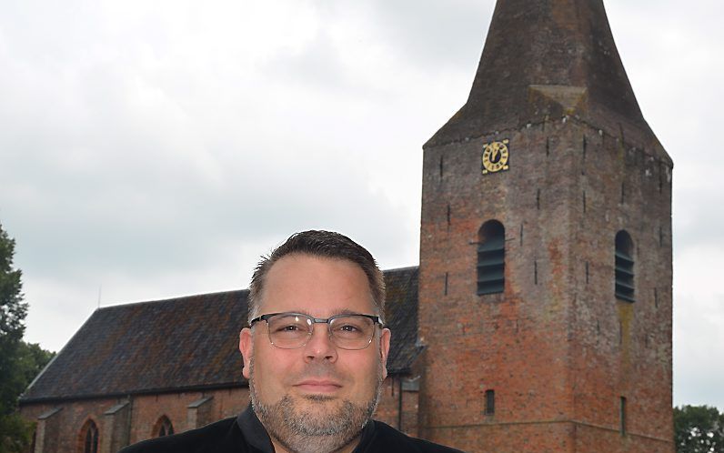 Ds. G. van den Berg, met op de achtergrond de hervormde kerk in Onstwedde. beeld hervormde gemeente Onstwedde