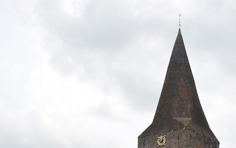 Ds. G. van den Berg, met op de achtergrond de hervormde kerk in Onstwedde. beeld hervormde gemeente Onstwedde