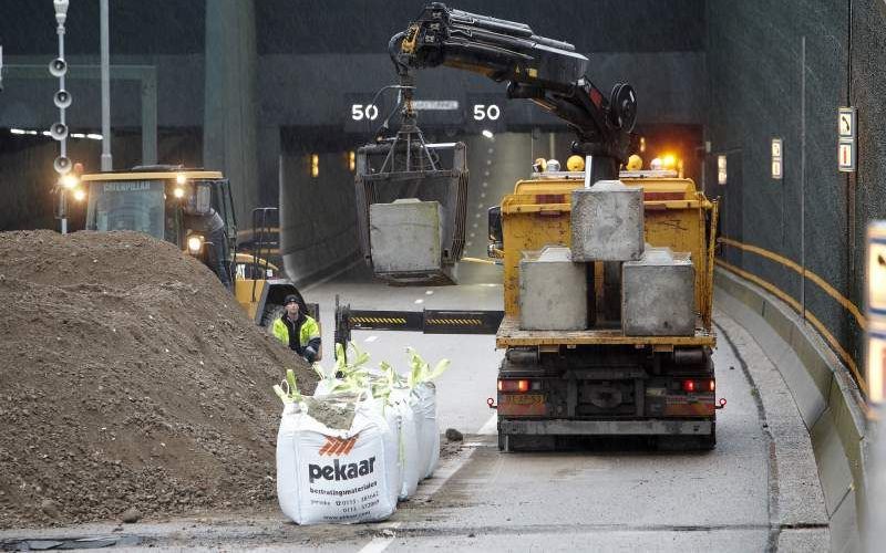 Een berg zand en betonblokken moeten zaterdag voorkomen dat de weg bij de Vlaketunnel tussen Bergen op Zoom en Vlissingen nog verder omhoog komt. Foto ANP