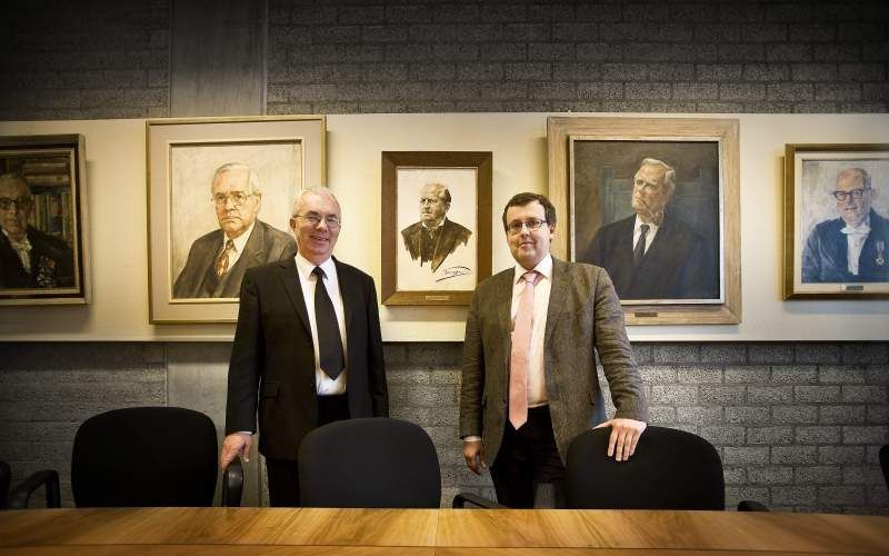 Prof. dr. F. A. van Lieburg (r.) en prof. dr. W. J. op ’t Hof in de theologische vergaderzaal van de VU, met op de achtergrond portretten van voormalige hoogleraren aan deze universiteit – Kuyper heeft de ereplaats in het midden. Foto RD, Henk Visscher