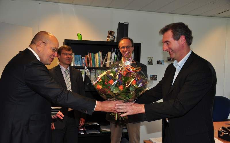 Staatssecretaris Teeven (l.) overhandigt een bloemetje aan de 500e vrijwilliger van Gevangenenzorg Nederland, Arie Bax (r.). Foto Gevangenenzorg Nederland