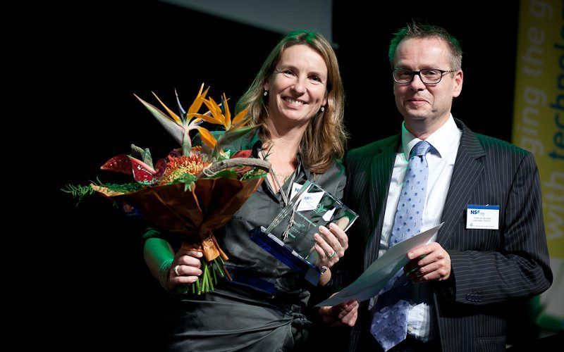 Winnaar Carola Wijdoogen van de NS. Folkert van der Molen, marketingmanager milieu en duurzaamheid bij Royal HaskoningDHV en juryvoorzitter, reikte de bokaal uit. beeld Nationaal Sustainability Congres