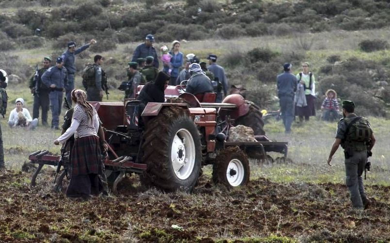 Israëlische soldaten verjagen Joodse kolonisten die proberen te verhinderen dat een Palestijnse boer zijn akker in de Westelijke Jordaanoever ploegt. Foto EPA