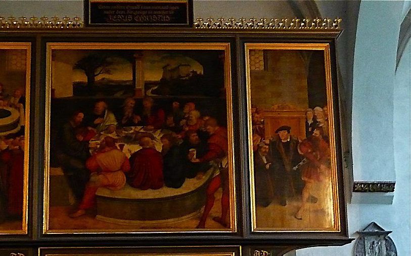 Lucas Cranach der Ältere schilderde Melanchthon (linksboven) op het Reformationsaltar in Wittenberg terwijl hij een druipend kind boven de doopvont houdt.  Foto RD/Archief