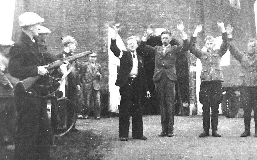 Een dag na de bevrijding van Dokkum. Twee Nederlandse SS’ers en de NSB-burgemeester van Oostdongeradeel worden onder schot gehouden. Op de achtergrond een van de twee molens op het Baantjebolwerk, waar het aangehouden trio voor straf graan moest gaan sjou