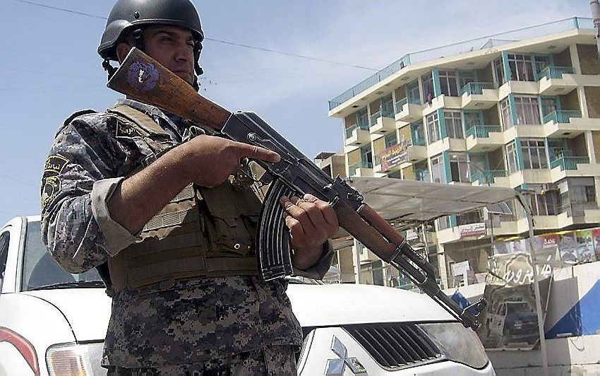 Een zwaarbewapende politieman controleert voertuigen in de Iraakse hoofdstad Baghdad. De Iraakse regering liet kerkgebouwen in het hele land gisteren extra bewaken. Foto EPA