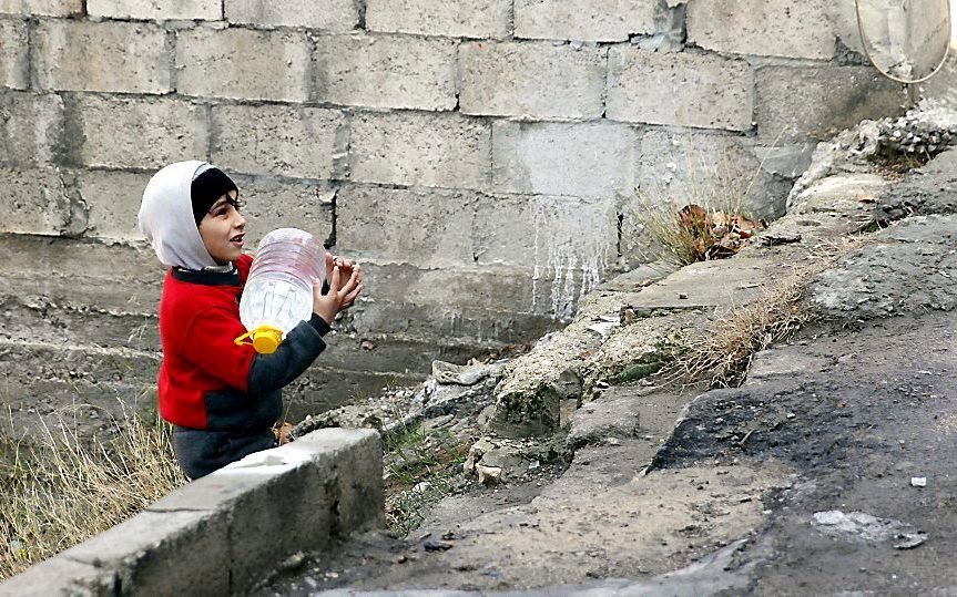 Een Syrisch jongetje in Damascus draagt een jerrycan met water. Rebellen hebben de watertoevoer in de hoofdstad afgesneden. beeld EPA