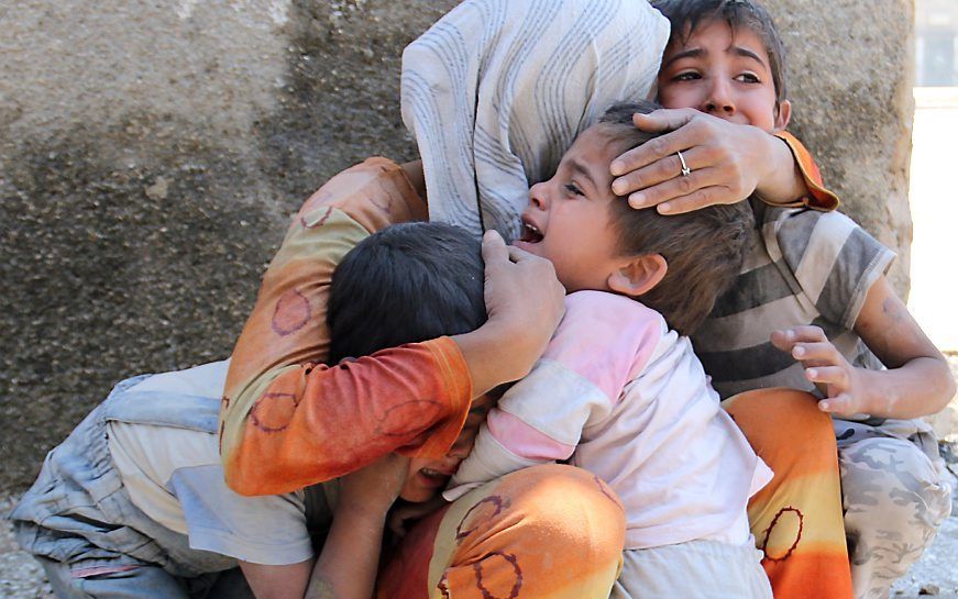 Een vrouw probeert haar kinderen te troosten nadat hun woning in Aleppo is gebombardeerd. Foto AFP