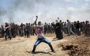 Een Palestijnse betoger slingerde maandag een steen richting Israëlische soldaten bij de grens tussen de Gazastrook en Israël. Bij confrontaties rond de grens zouden gisteren zeker 58 doden zijn gevallen. beeld EPA, Luca Piergiovanni