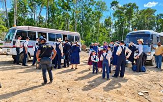 De Surinaamse politie haalt mennonietengezinnen weg. Op het zanderige terrein staan twee busjes.