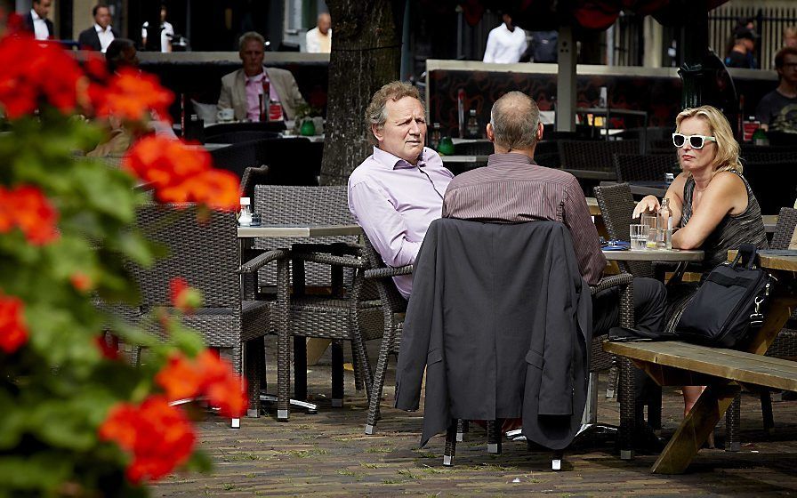 GroenLinks-fractievoorzitter Bram van Ojik (L) is op een terras op het Plein in gesprek met minister Jet Bussemaker (R) van Onderwijs en haar politiek assistent. Het kabinet is in overleg over de begroting van volgend jaar. Foto ANP