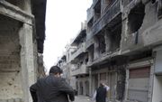 Een Syrische predikant stapt over het puin in de deels verwoeste stad Homs. Bij de puinhopen neerzitten is geen optie voor veel christenen in het land, maar verder maakt iedereen zijn eigen keuzes. beeld Jacob Hoekman