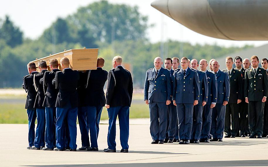 Militairen dragen in augustus op vliegbasis Eindhoven een kist met daarin de resten van slachtoffers van de vliegramp met de MH17 in Oekraine. Beeld ANP