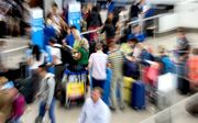 Reizigers haasten zich naar de incheckbalie op Schiphol. De luchthaven verwacht deze zomer topdrukte met 12,7 miljoen passagiers. beeld ANP, Koen van Weel