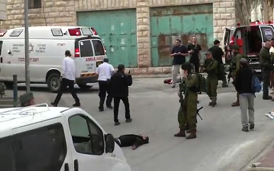 HEBRON. Een gewonde Palestijn ligt op de grond in Hebron, kort voor een Israëlische soldaat hem door het hoofd schiet. beeld AFP