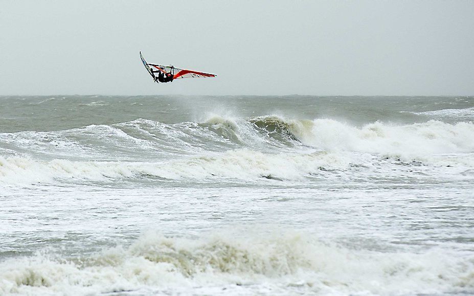 Een surfer maakt een sprong tijdens de zuidwesterstorm op het Scheveningse strand. Beeld ANP