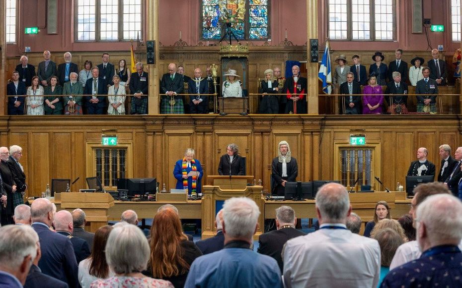 De synode van de Church of Scotland luistert naar scriba Fiona Smith, die een brief van koning Charles III voorleest. beeld Church of Scotland