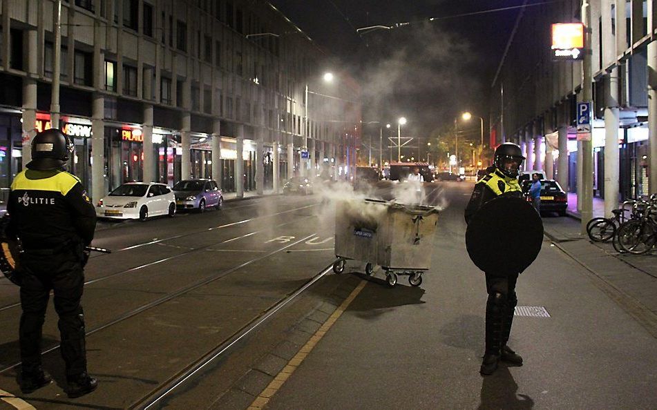 Politie bij een brandende container in de Schilderswijk, in de nacht naar woensdag. Beeld ANP