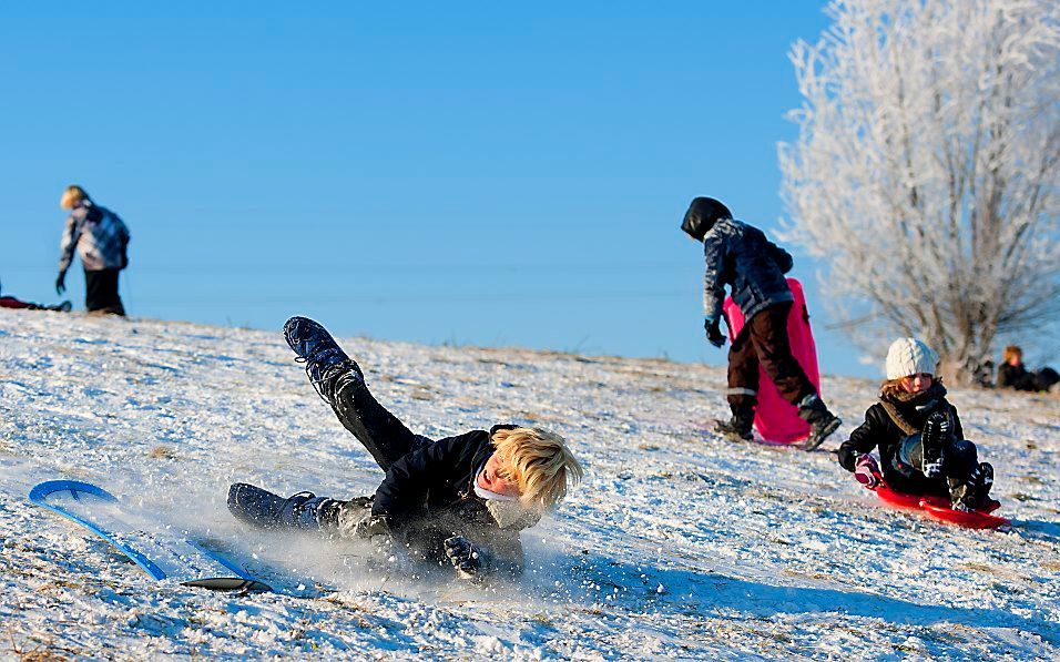 Met een lekker winters zonnetje genieten veel ouders met hun kinderen van het sleetje rijden in de amsterdamse wijk IJburg. Foto ANP