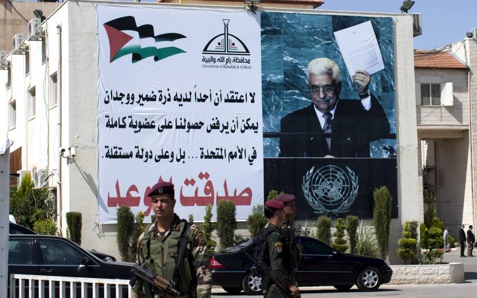 Palestijnen in Ramallah, op de Westelijke Jordaanoever, bij een billboard met de Palestijnse president Abbas. Foto EPA