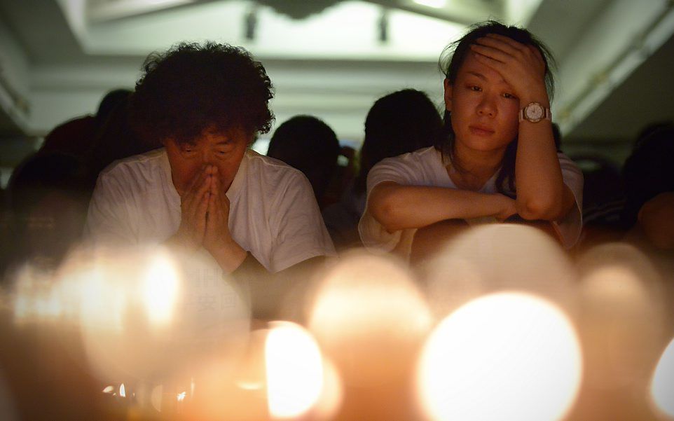 Nabestaanden van inzittenden in gebed in een hotel in Beijing. Foto AFP