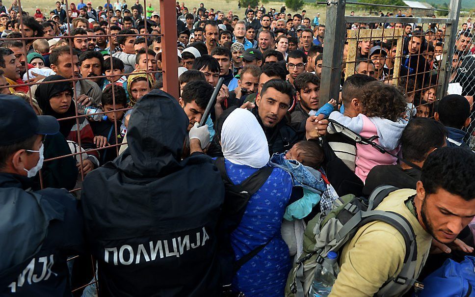 Migranten berken door een politiecordon in Macedonie. Beeld EPA