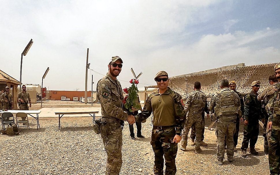 Een Amerikaanse en een Afghaanse militair schudden elkaar de hand tijdens een overdrachtsmoment in Helmand. beeld EPA, Ministry of Defence