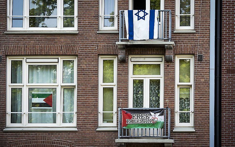 Israëlische en Palestijnse vlaggen hangen aan balkons in Amsterdam. De spanning in de hoofdstad loopt op door het conflict in Israel en de Gazastrook. beeld ANP