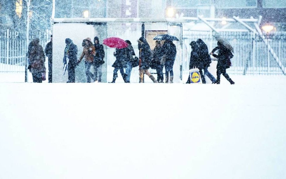 Reizigers, onder wie leerlingen, wachtten vrijdag in de sneeuw bij een bushalte in Rotterdam. Veel scholen waren vrijdag gesloten vanwege de winterse omstandigheden.	Foto ANP