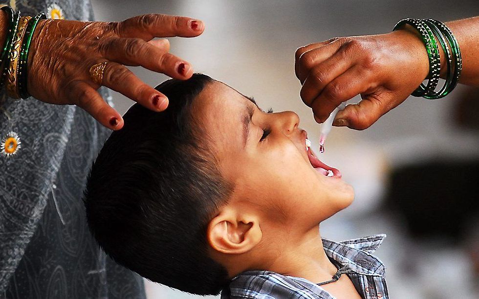 Een Indiase gezondheidswerker geeft een jongetje twee druppels poliovaccin. Internationale organisaties hopen de ziekte. Foto EPA