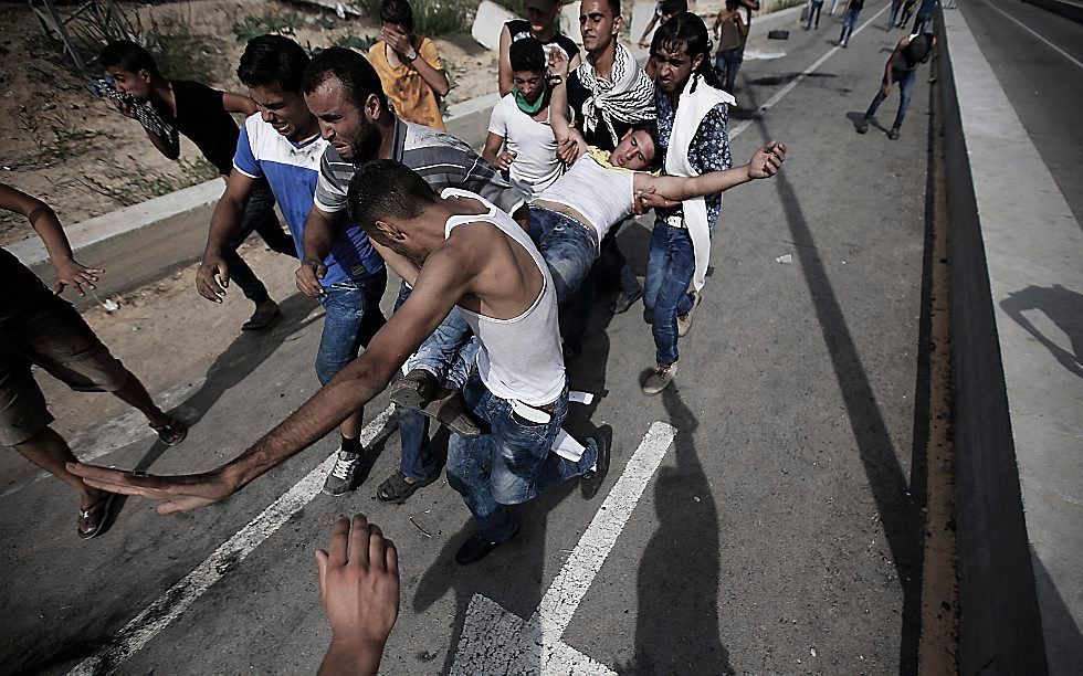 Palestijnen in de Gazastrook dragen een gewonde weg, na botsingen met de Israelische politie. Beeld EPA