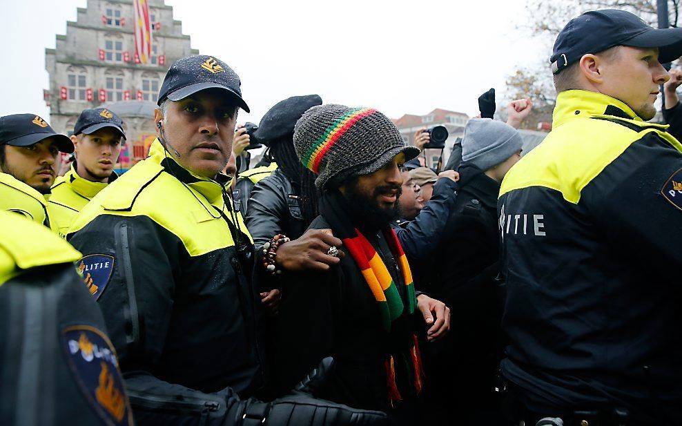 Een tegenstander van Zwarte Piet wordt weggeleid door politieagenten. Beeld ANP