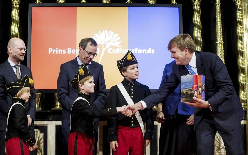 Koning Willem-Alexander kreeg vrijdagmiddag in de Nieuwe Kerk in Amsterdam de biografieën van de koningen Willem I, II en III overhandigd. De boeken werden binnengedragen door drie jongens die Willem heten. Achter hen de auteurs, van links naar rechts: dr