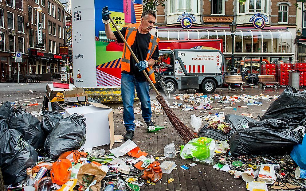 Een schoonmaker veegt de straten schoon na drie dagen staken. beeld ANP